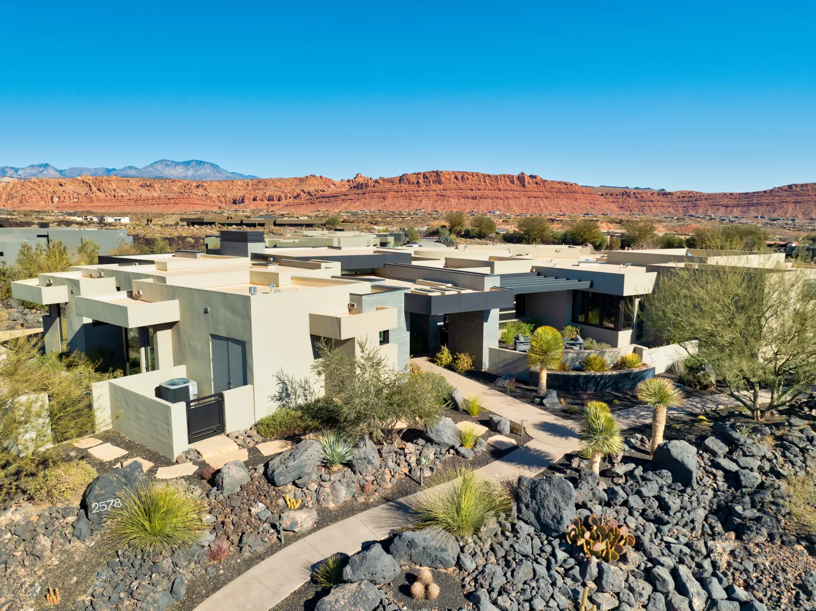 A modern desert home with red rock cliffs and mountains beyond